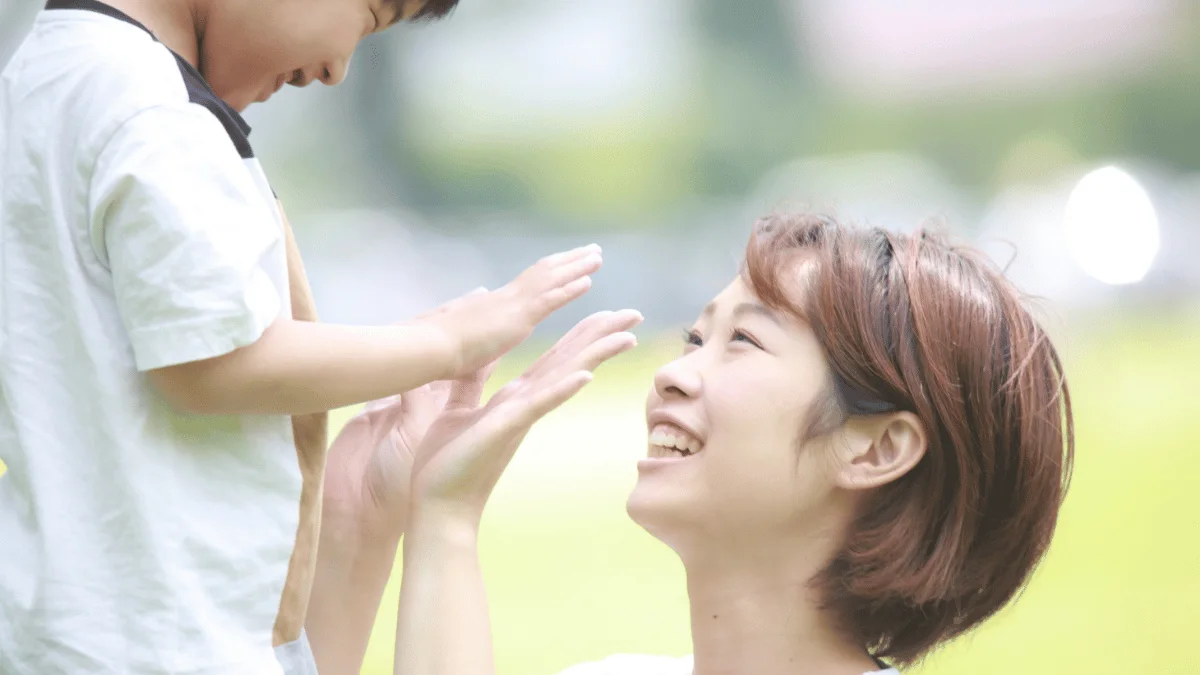 手を合わせて笑い合うお母さんと子ども